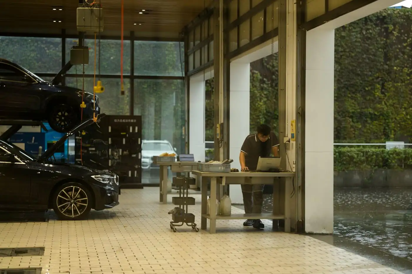 A mechanic working on a laptop at a workbench in a bright workshop