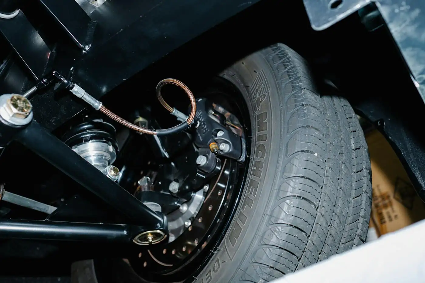 Close-up of a car wheel, tyre and brake hose from underneath